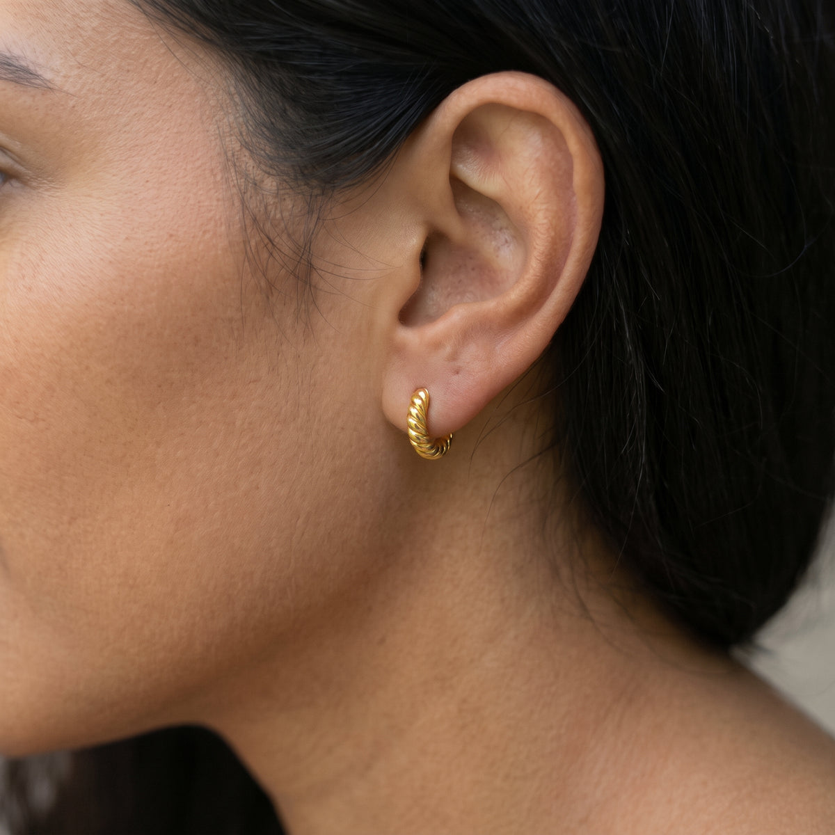 14K solid gold twisted huggie hoop earrings worn in ear
