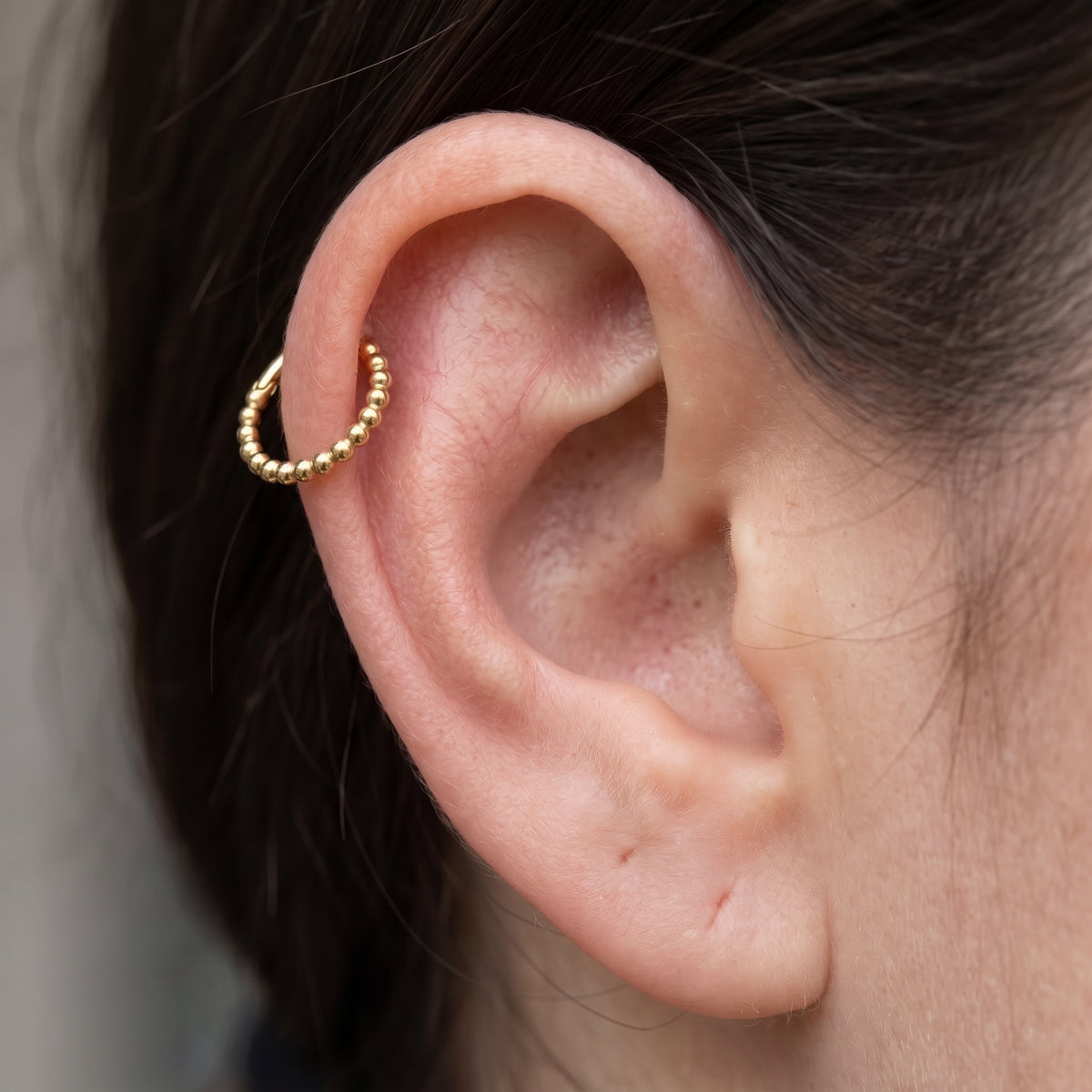 10K solid gold beaded clicker hoop worn in cartilage piercing